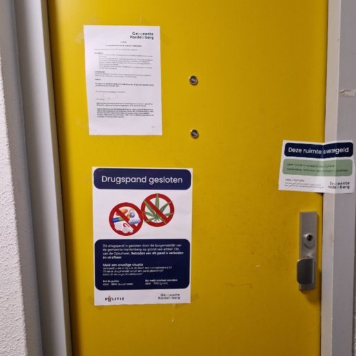 Foto van voordeur gesloten drugspand, met op die deur allerlei gemeentelijke uitlatingen dat het om een drugspand gaat en wat dat betekent